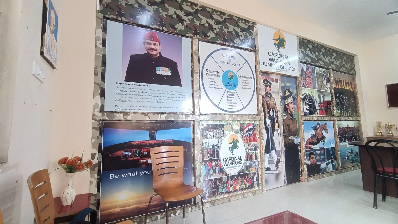 Indoor wall gallery at Cardinal Warriors military school with framed posters, cadet and event photos, and trophies on a side table