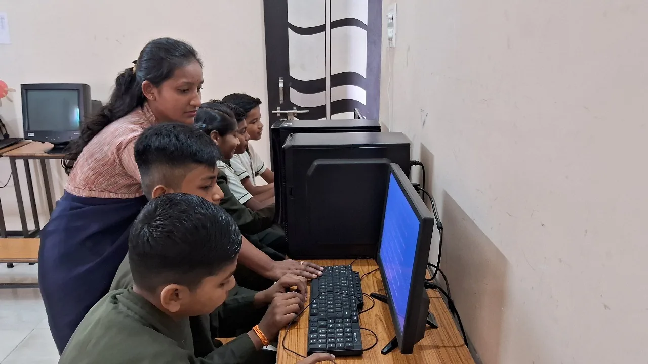 Cadets in olive uniform working at desktop computers in the Cardinal Warriors computer lab, supervised by a teacher.
