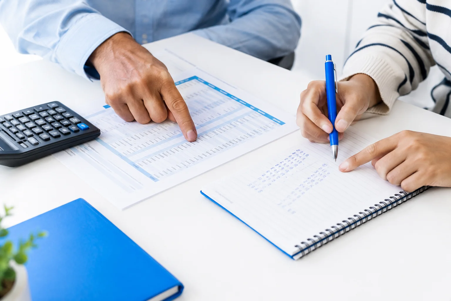 Calculator, notebook and fee papers on a desk used to plan total pilot training cost