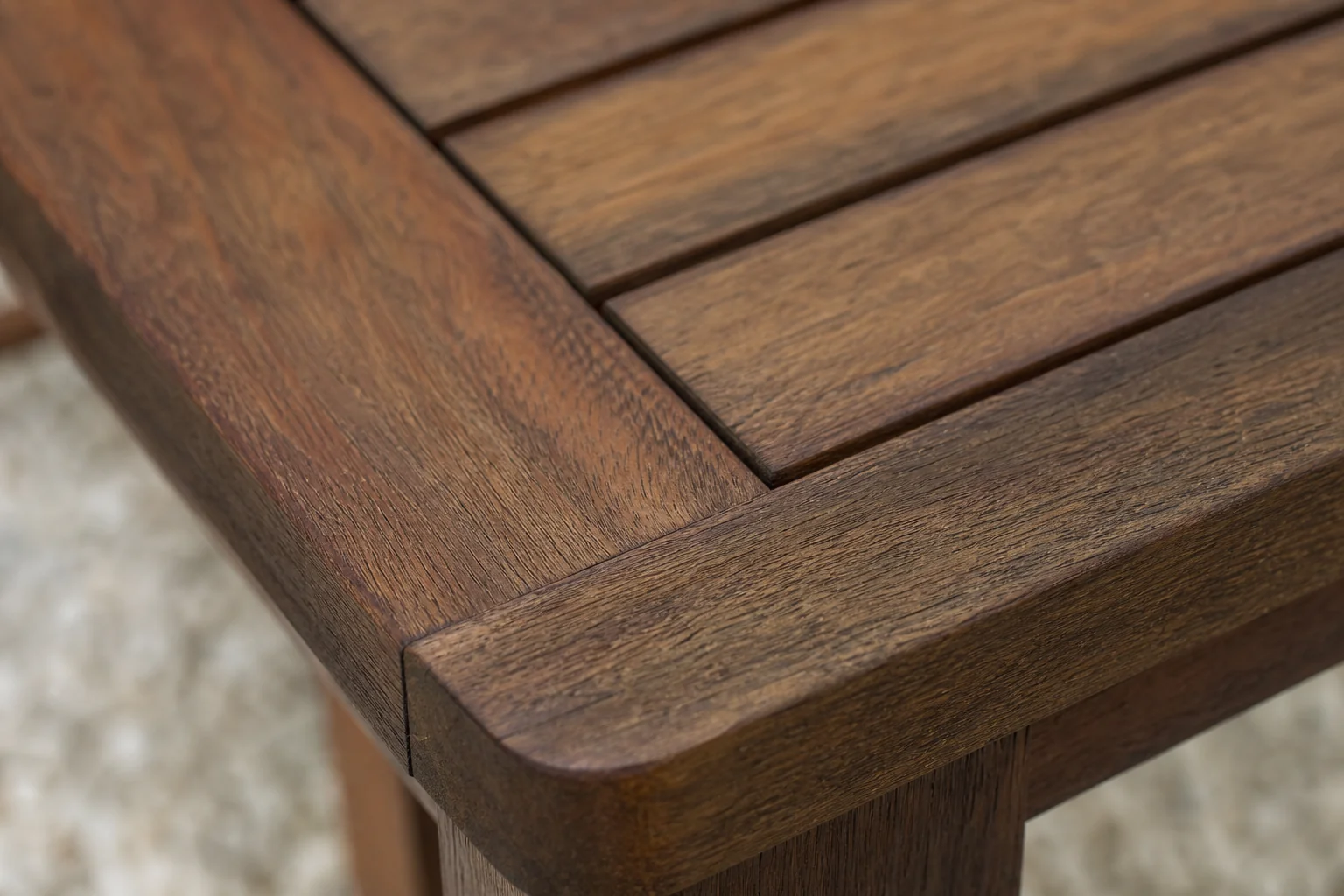 Close-up of weathered teak wood grain showing natural resilience. photorealistic close-up macro photograph of solid teak wood outdoor furniture surface, showing rich brown grain (#765139, #3f352a tones), subtle natural oil sheen, weathered