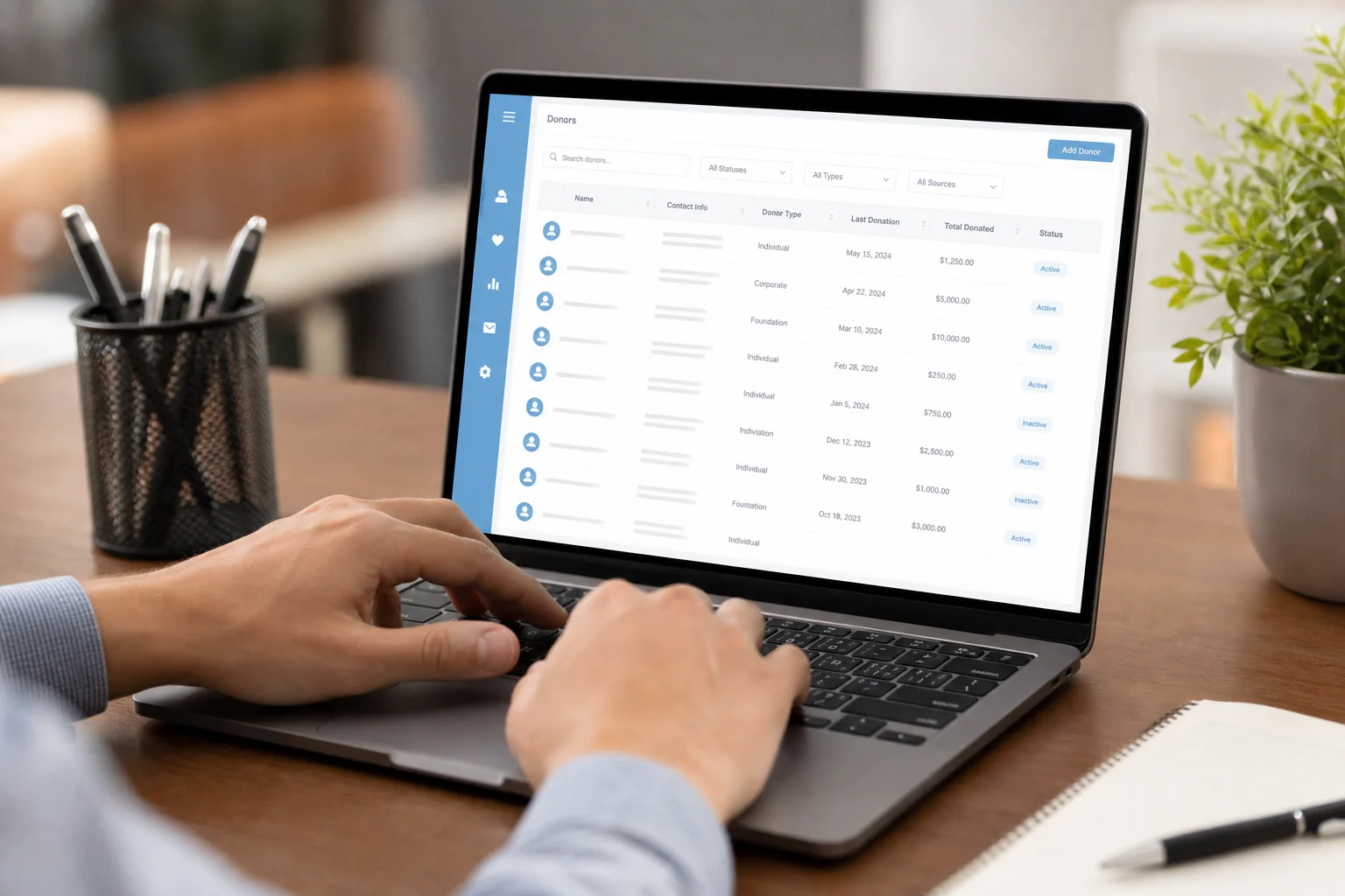 Close-up of hands organizing donor record cards or cleaning a database on screen. photorealistic close-up photo of a person's hands typing on a laptop keyboard with a donor database interface visible on screen showing organized contact