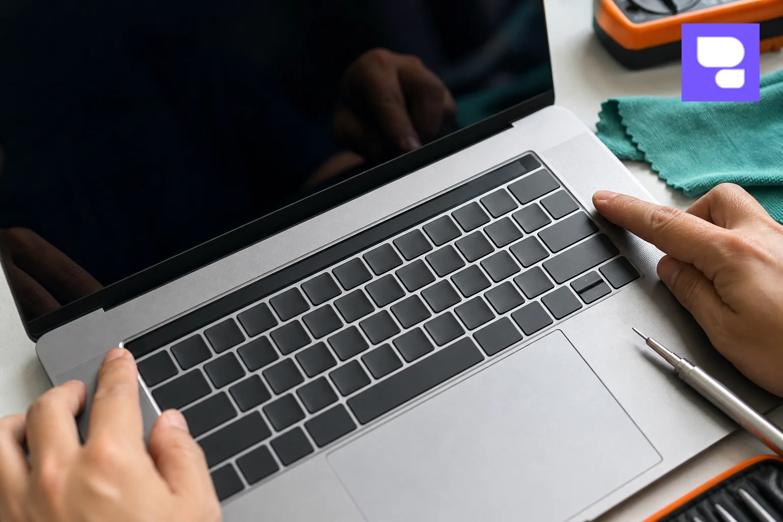 Close-up photo of a MacBook Pro with a dark, unresponsive Touch Bar being examined by a technician's hands. Photorealistic close-up photograph of a silver MacBook Pro keyboard and a dark, blank Touch Bar strip above it, with a technician's