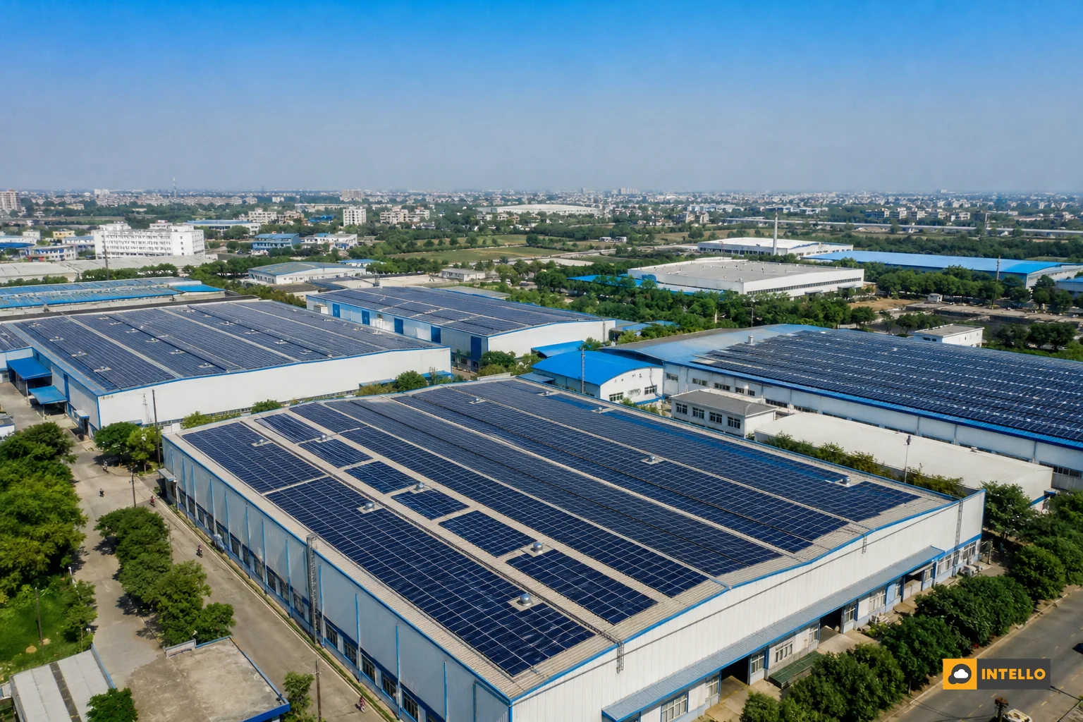 Aerial view of multiple commercial rooftop solar installations across different locations connected conceptually, representing a solar portfolio. Photorealistic aerial drone photo of several large commercial rooftop solar panel