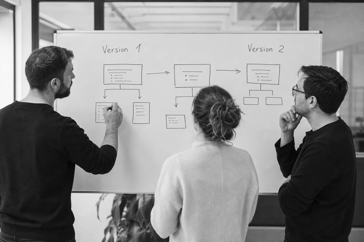 Whiteboard session showing a team sketching a phased MVP feature roadmap for a booking app. photorealistic photo: a small product team of three people around a whiteboard sketching a phased feature roadmap with boxes and arrows labeled