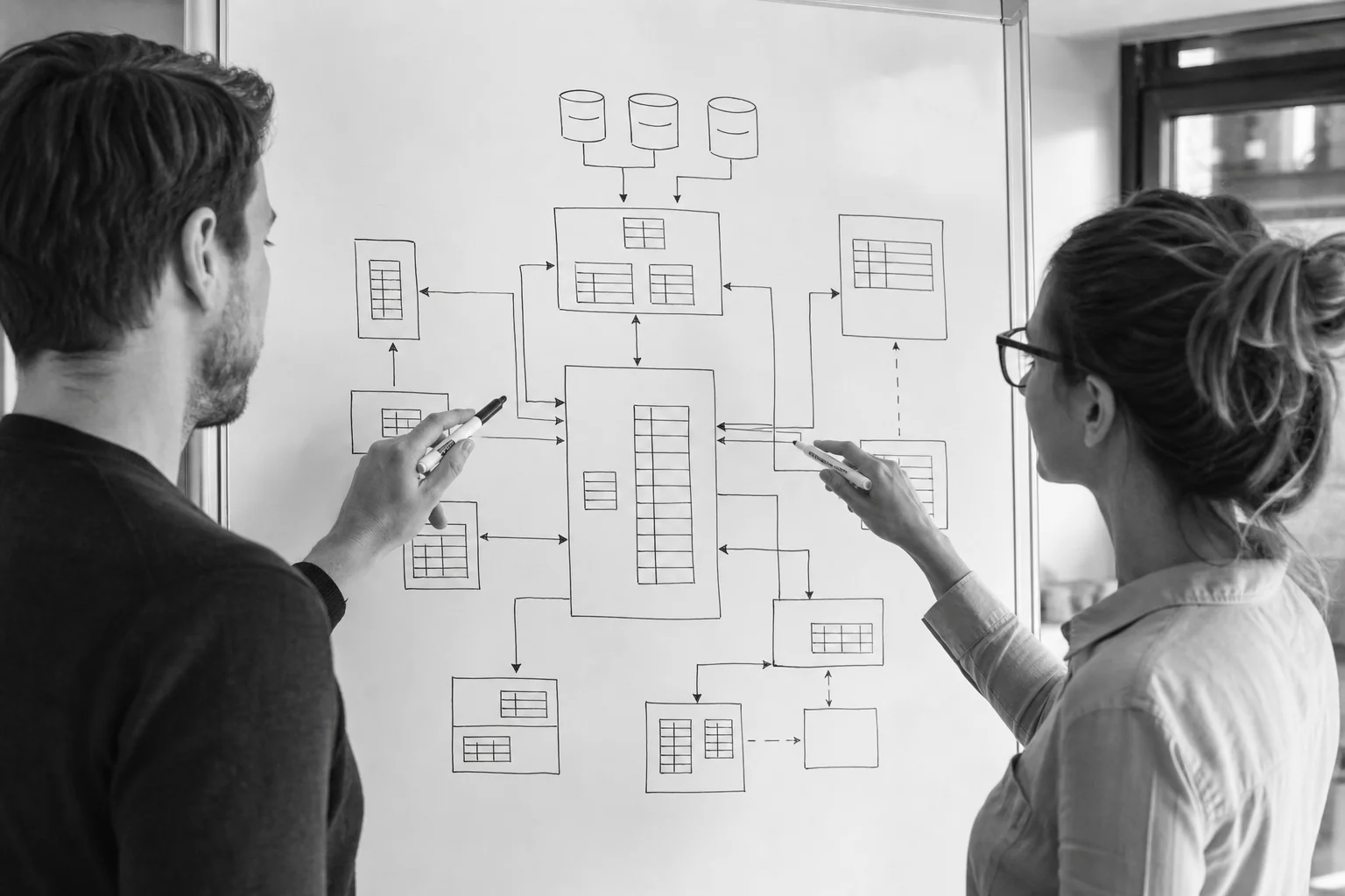 Two professionals mapping data fields between CRM and business systems on a whiteboard