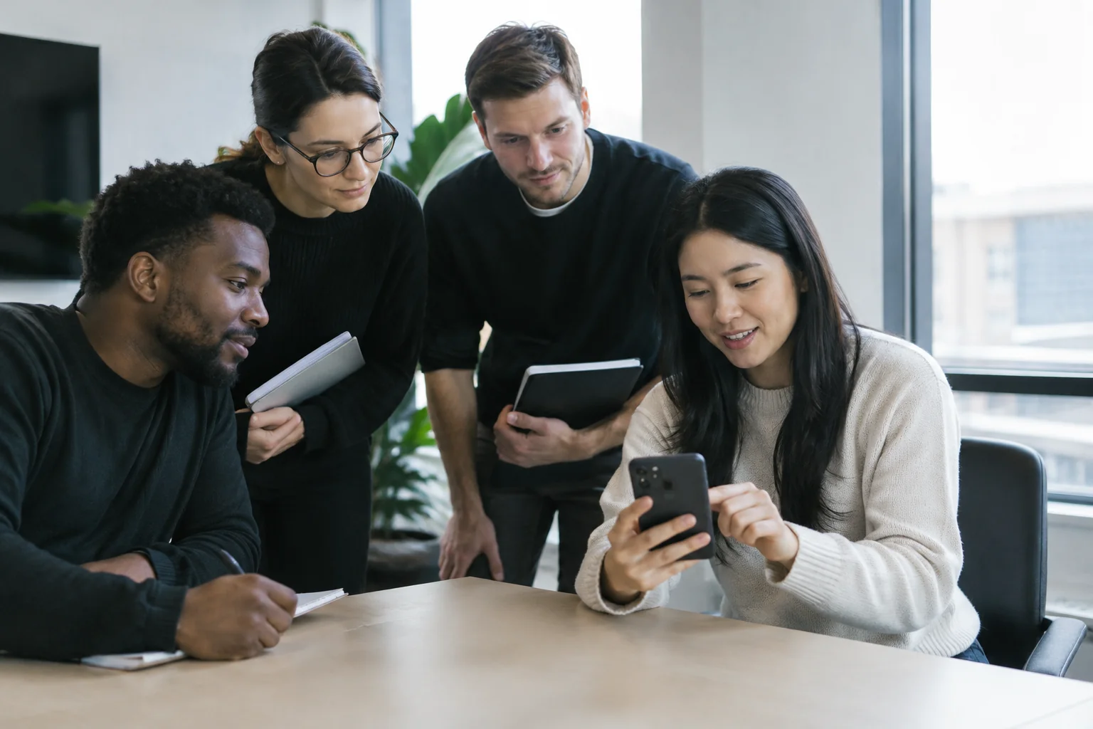 Small team watching early users try a working mobile app on a phone during a feedback session