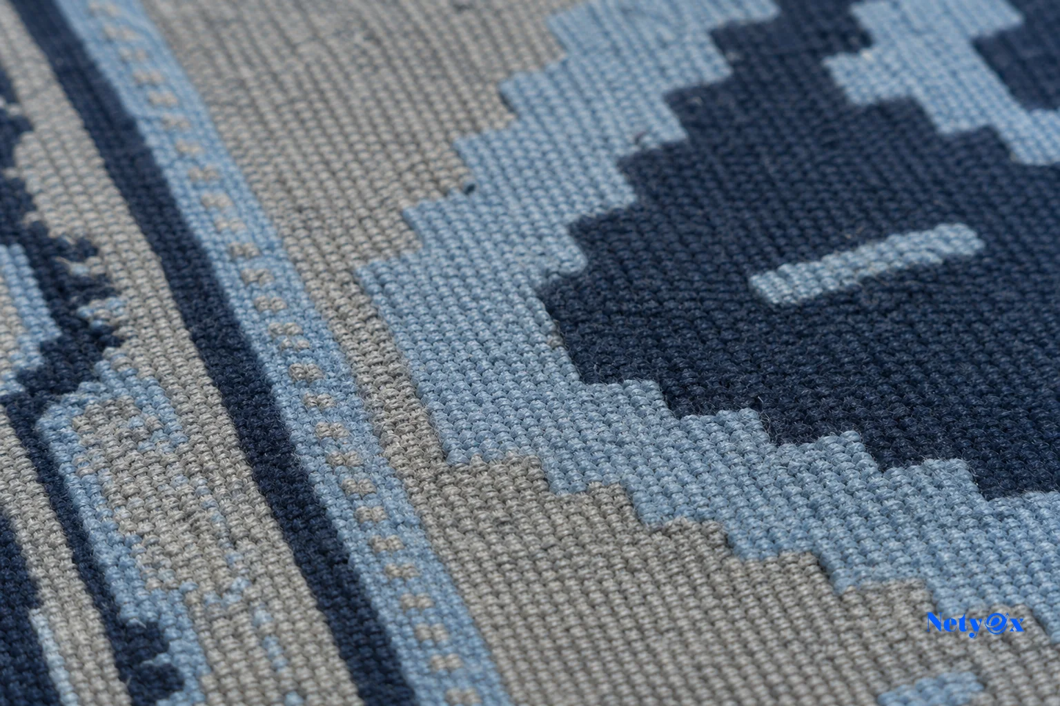 Close-up macro photo of a hand-woven cotton flatweave rug showing tight warp and weft threads. Photorealistic macro close-up photograph of a hand-woven cotton flatweave dhurrie rug surface, showing detailed warp and weft thread structure