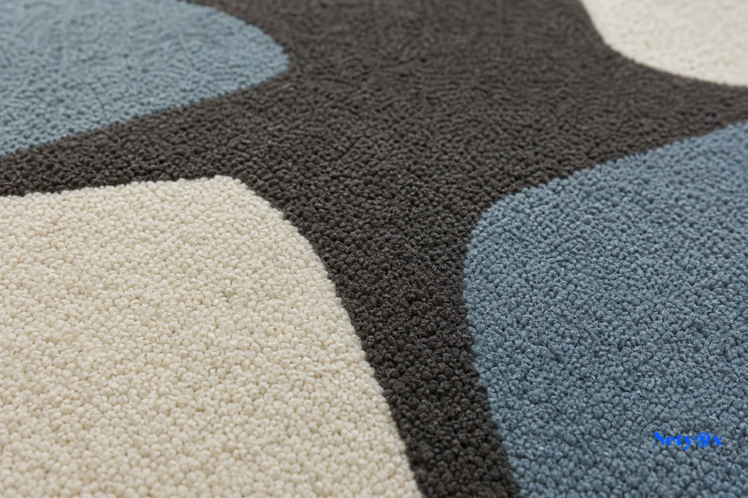 Close-up of hand-tufted wool rug texture showing pile and craftsmanship. Photorealistic close-up photograph of a hand-tufted wool rug surface showing dense pile texture and a modern abstract geometric pattern in charcoal, ivory, and muted