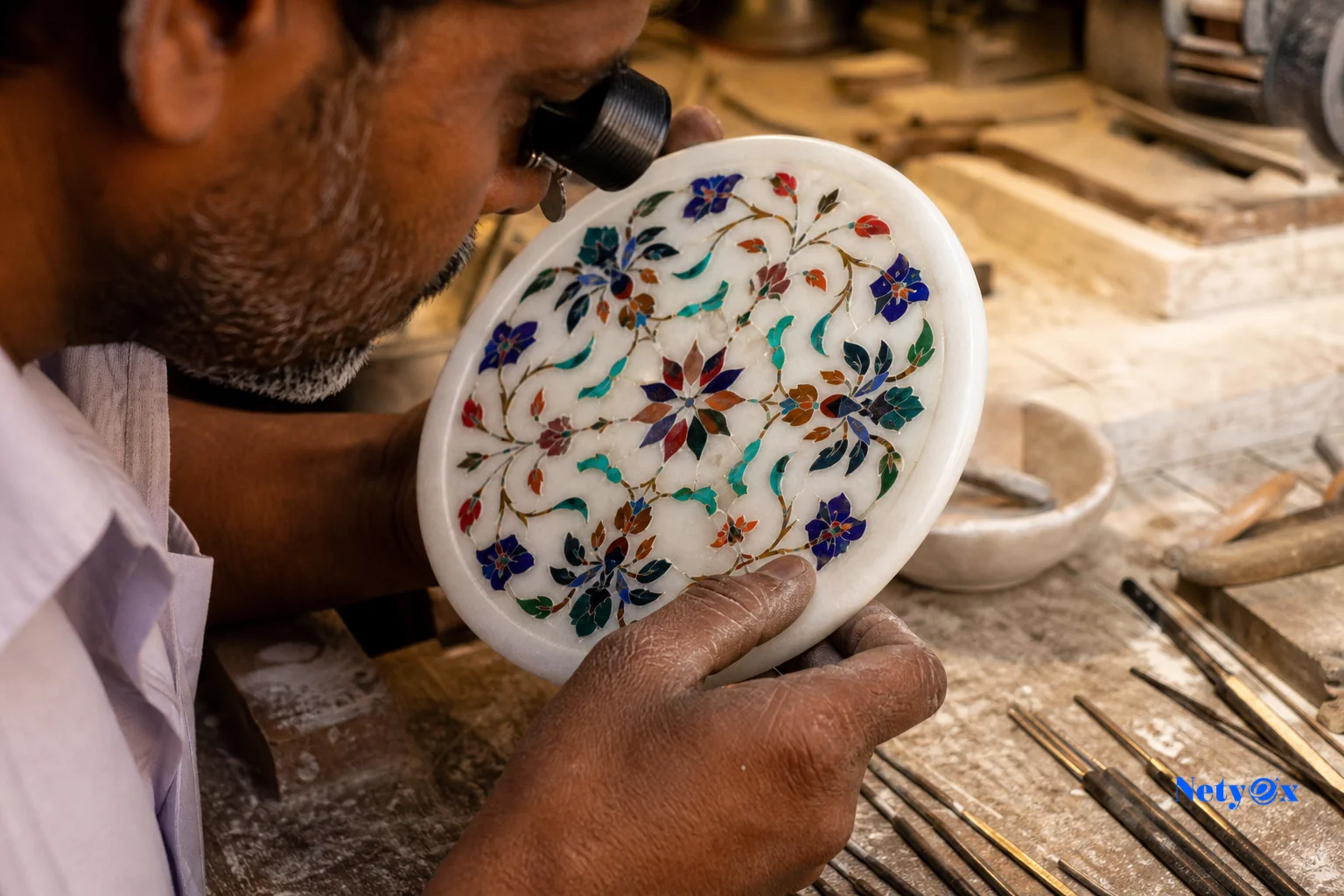 Artisan hands inspecting marble inlay handicraft quality in an Indian workshop using magnification tools