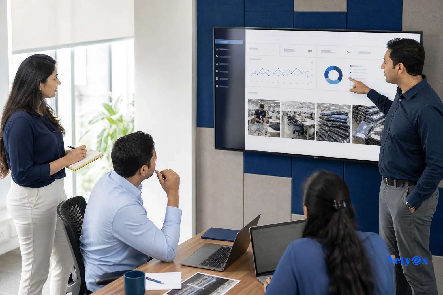 Team coordinating production monitoring in an India sourcing office. photorealistic photo of a small sourcing office team in India reviewing production photos and shipment documents on a large monitor, dedicated specialist pointing at a
